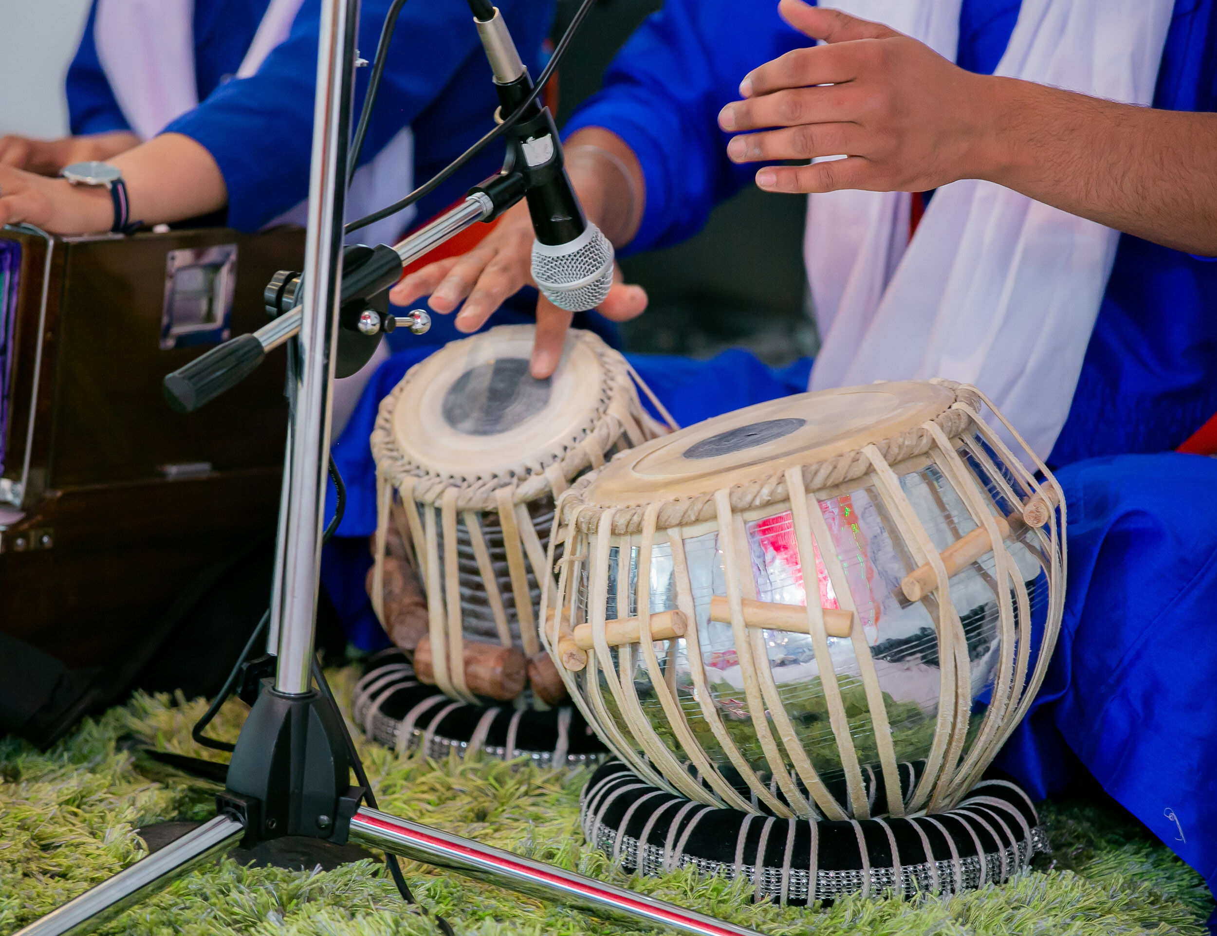 Musicians playing traditional Indian tabla drums during a cultural or wedding ceremony, with microphones capturing the live performance
